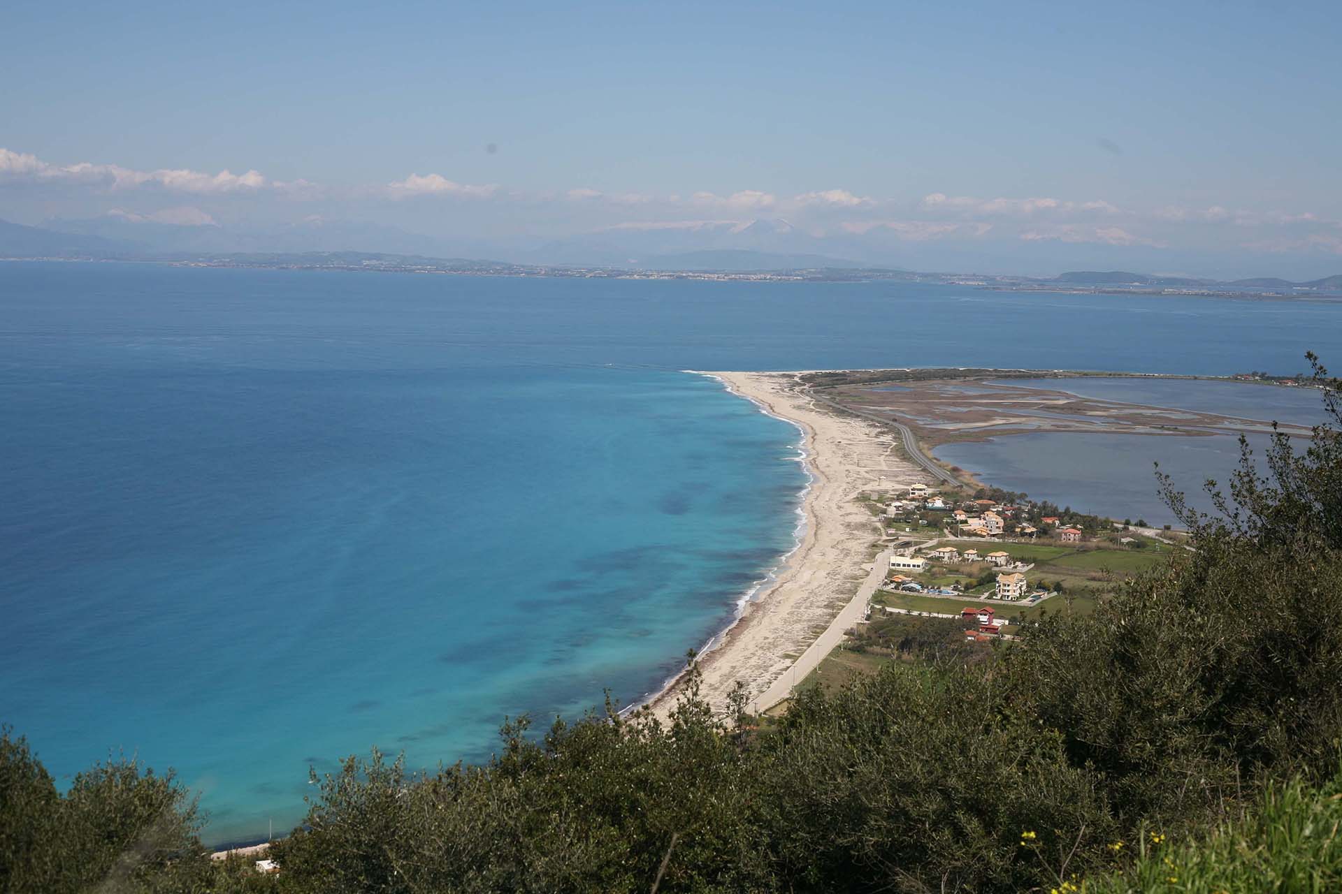 Dozens of colorful kites from kitesurfers on the turquoise waters of Agios Ioannis Beach, Lefkada.