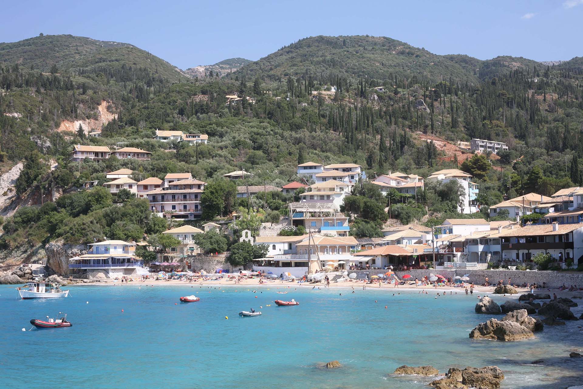 Τα κρυστάλλινα τυρκουάζ νερά της παραλίας του Αγίου Νικήτα, με το γοητευτικό χωριό στο βάθος.