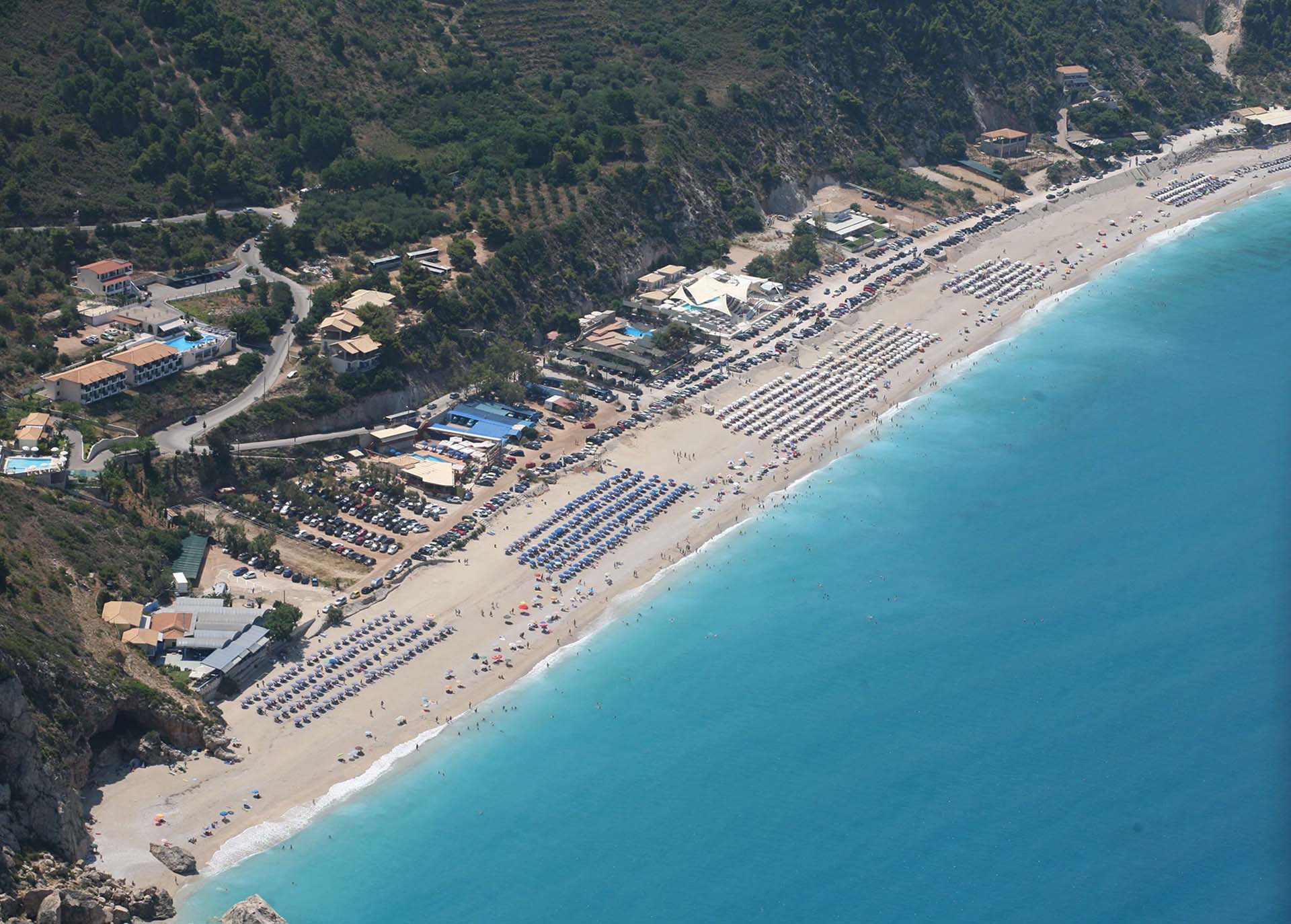 Μια εκτεταμένη αεροφωτογραφία της μεγάλης, αμμώδους παραλίας Κάθισμα, με τα διάσημα τυρκουάζ νερά και τα ζωντανά beach bar.