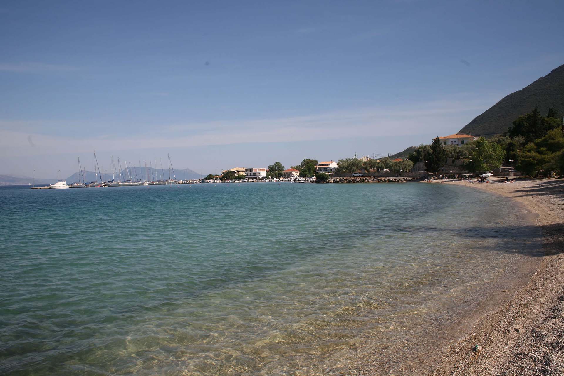 Τα ήρεμα, καθαρά νερά και η βοτσαλωτή ακτή της παραλίας της Λυγιάς, με ψαροκάικα στο γραφικό λιμάνι.