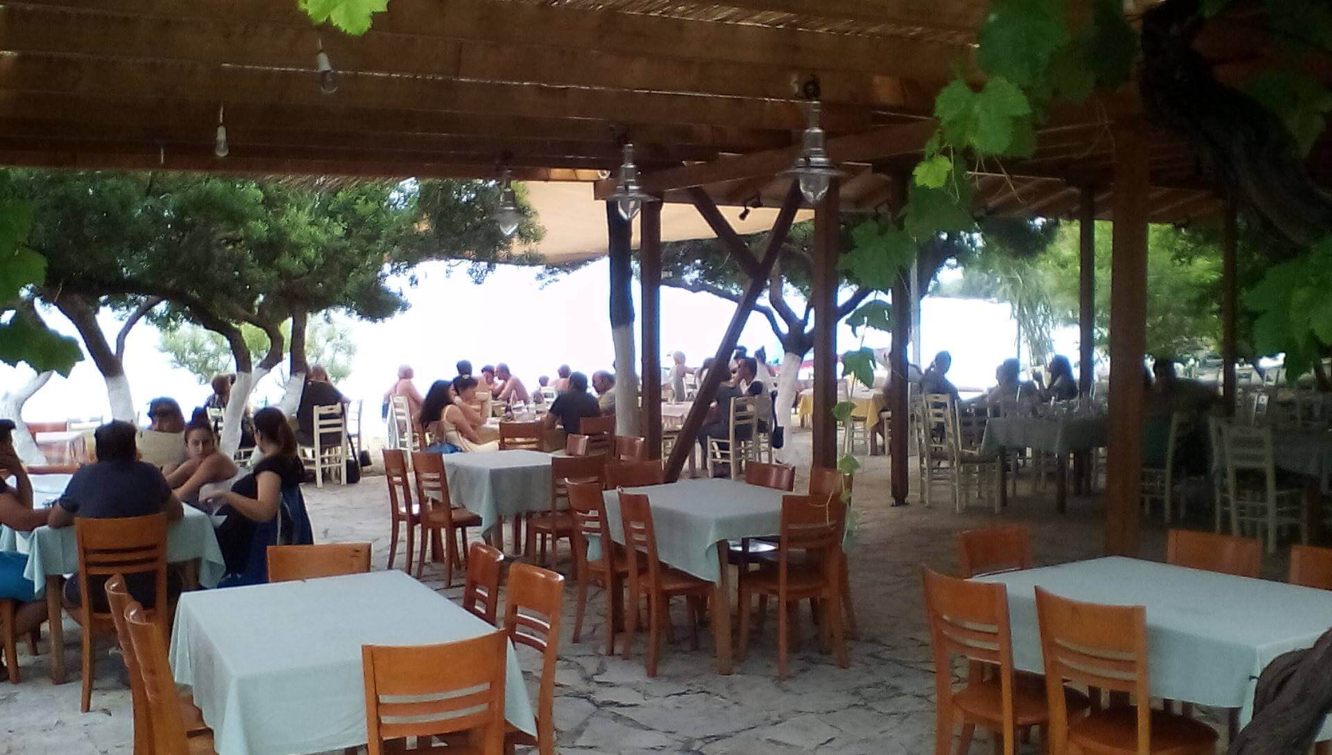 The beautiful seaside setting of Breath of Zorbas in Nikiana, with dining tables and sunbeds on the beach.
