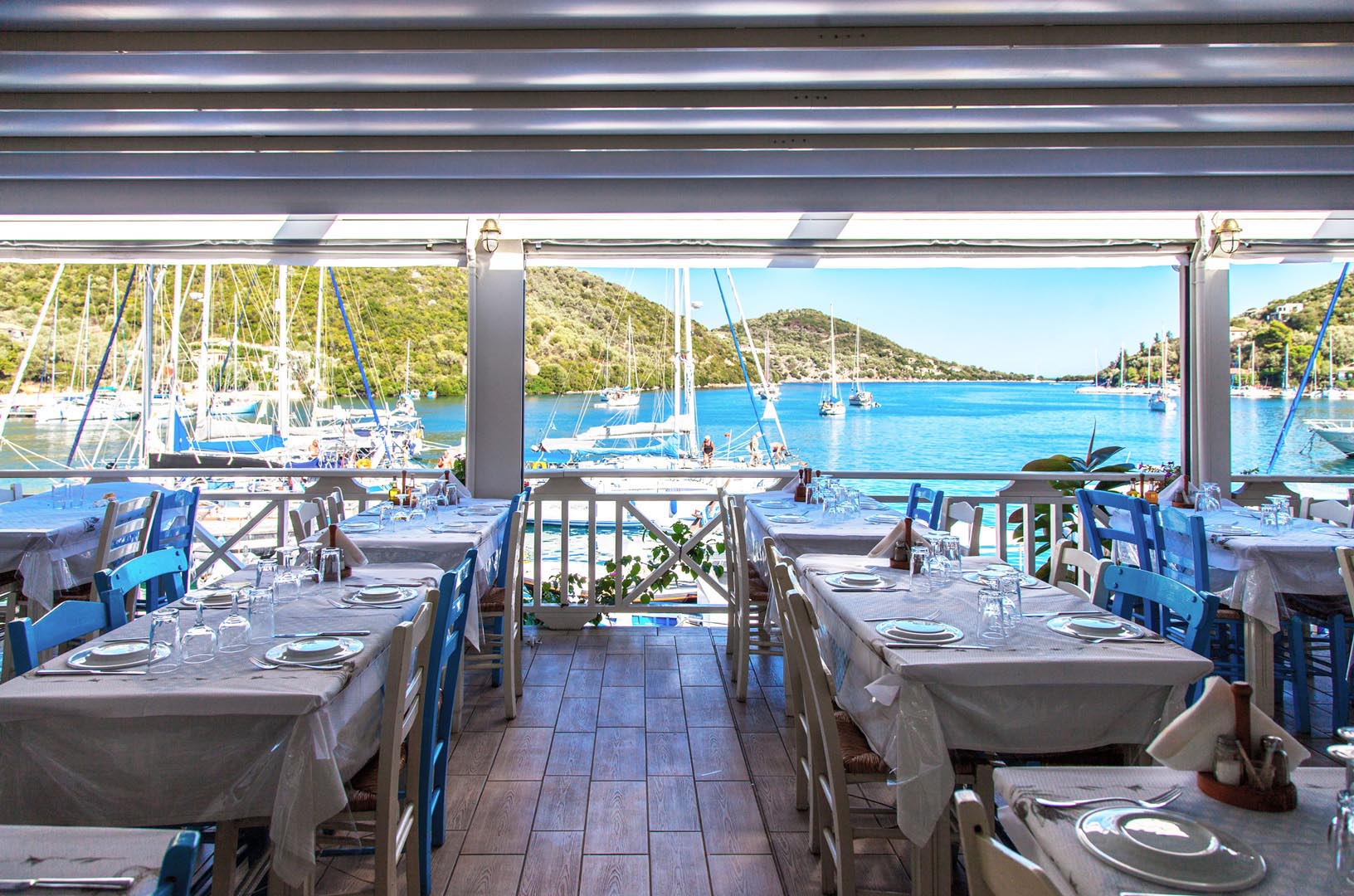 Η ψαροταβέρνα Σταύρος στο γραφικό λιμάνι των Συβότων Λευκάδας, με τραπέζια δίπλα στην ήρεμη θάλασσα.