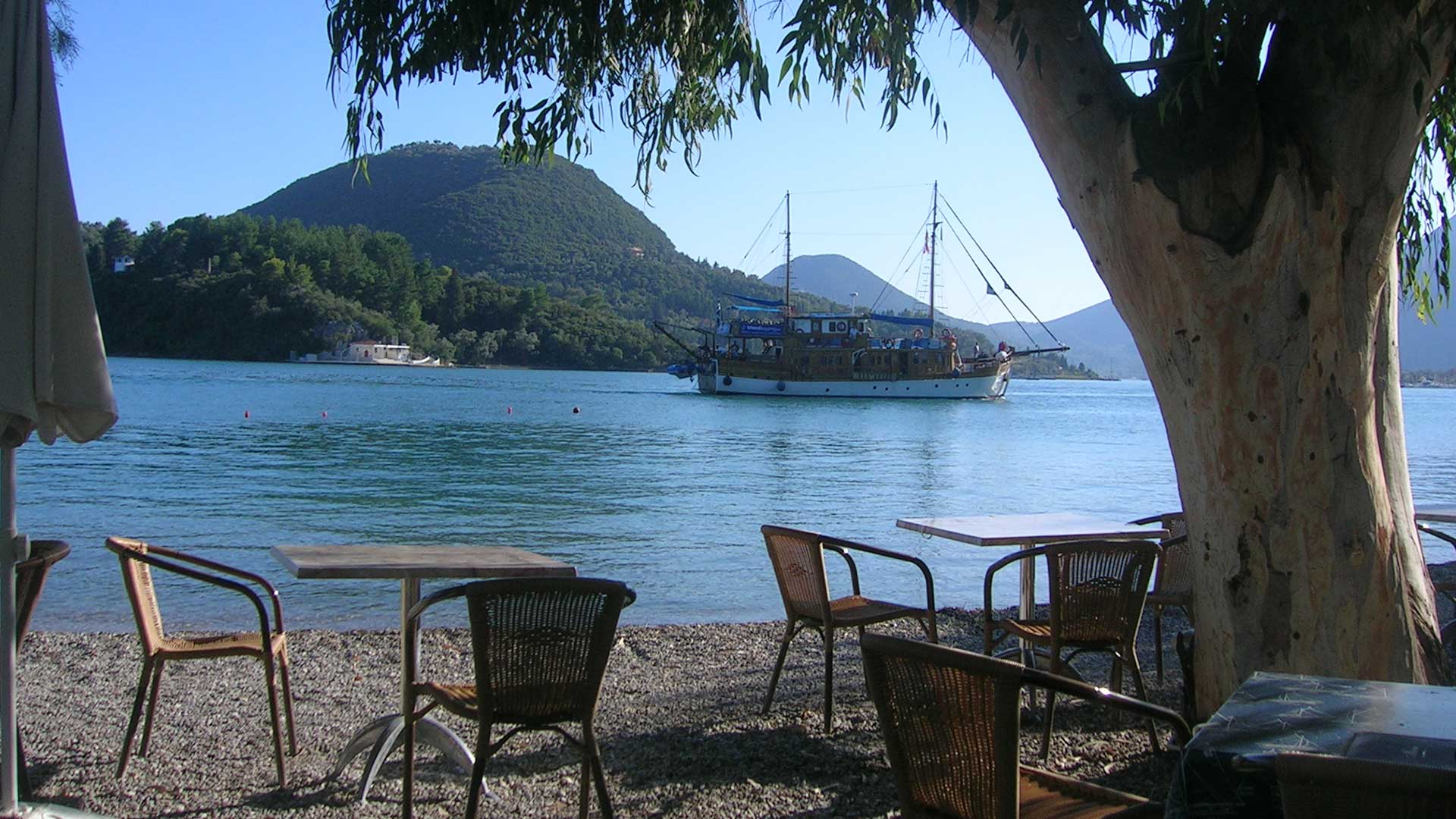 Romantic candlelight dinner setting at Tom's Sea Side Restaurant, with tables right next to the water in Nidri, Lefkada.
